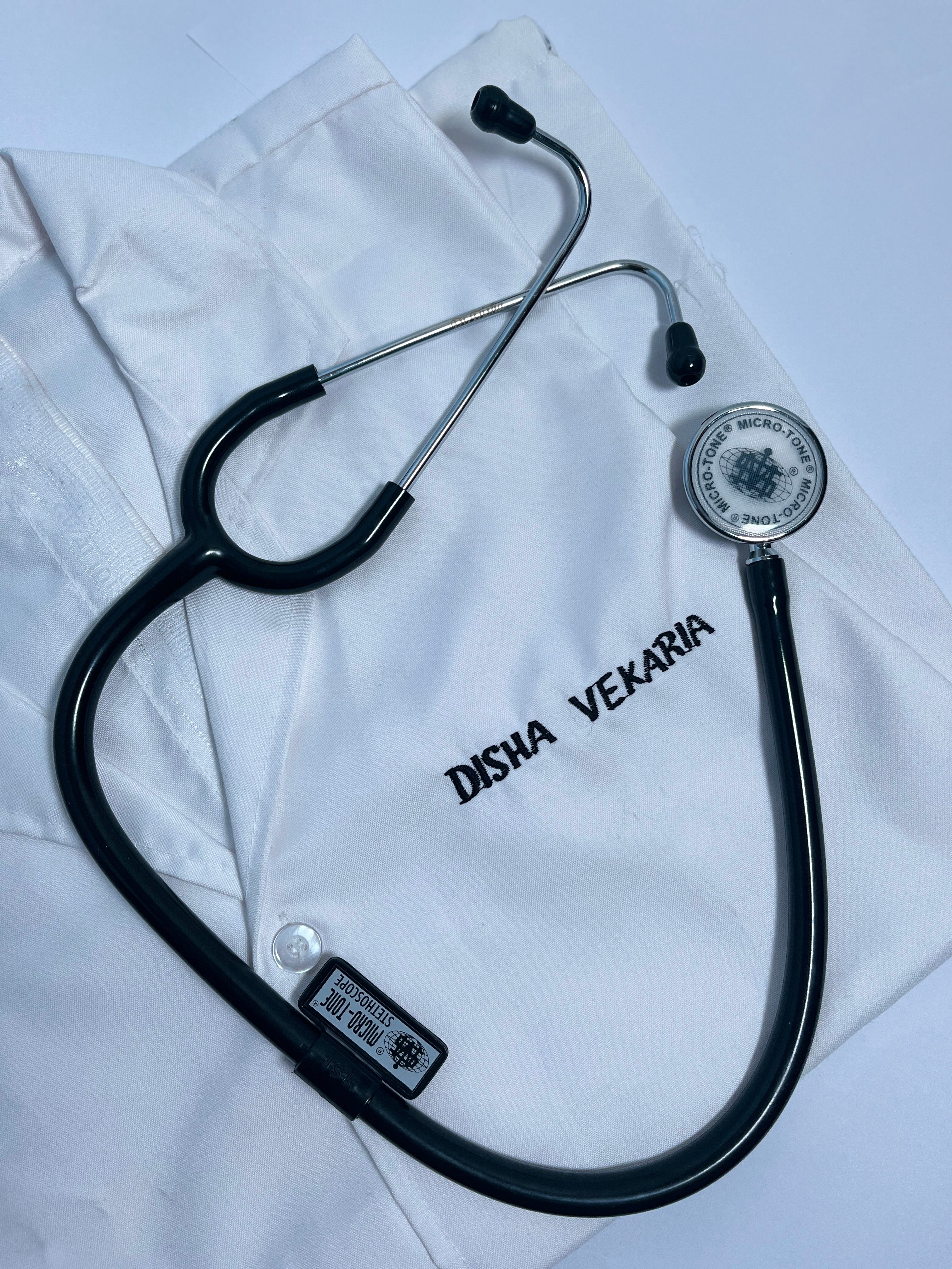 Stethoscope on a white coat with 'Disha Vekaria' branding.